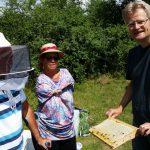 Reinhold zeigt den Bienenpaten Anne und Hans Zirkel eine Honigwabe